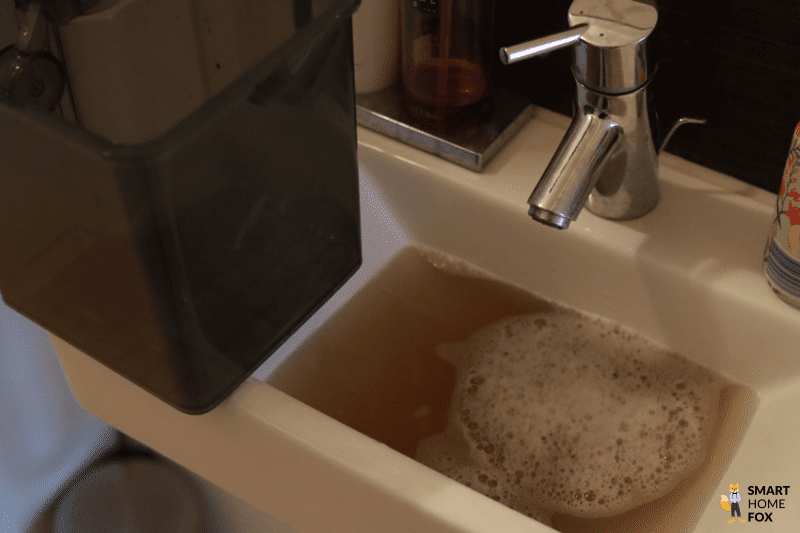 Der Schmutzwassertank des ECOVACS DEEBOT X2 OMNI wird am Waschbecken ausgeleert.